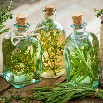 Tre klara glasflaskor fyllda med smaksatt olja, stängda med en kork